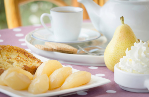 French Pear table setting with a cup and saucer, pears, whipped cream and cake