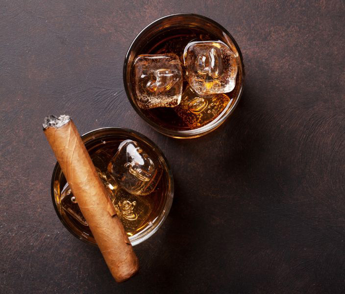 Whiskey, smoke and leather Two glasses of whiskey and a cigar on a leather background